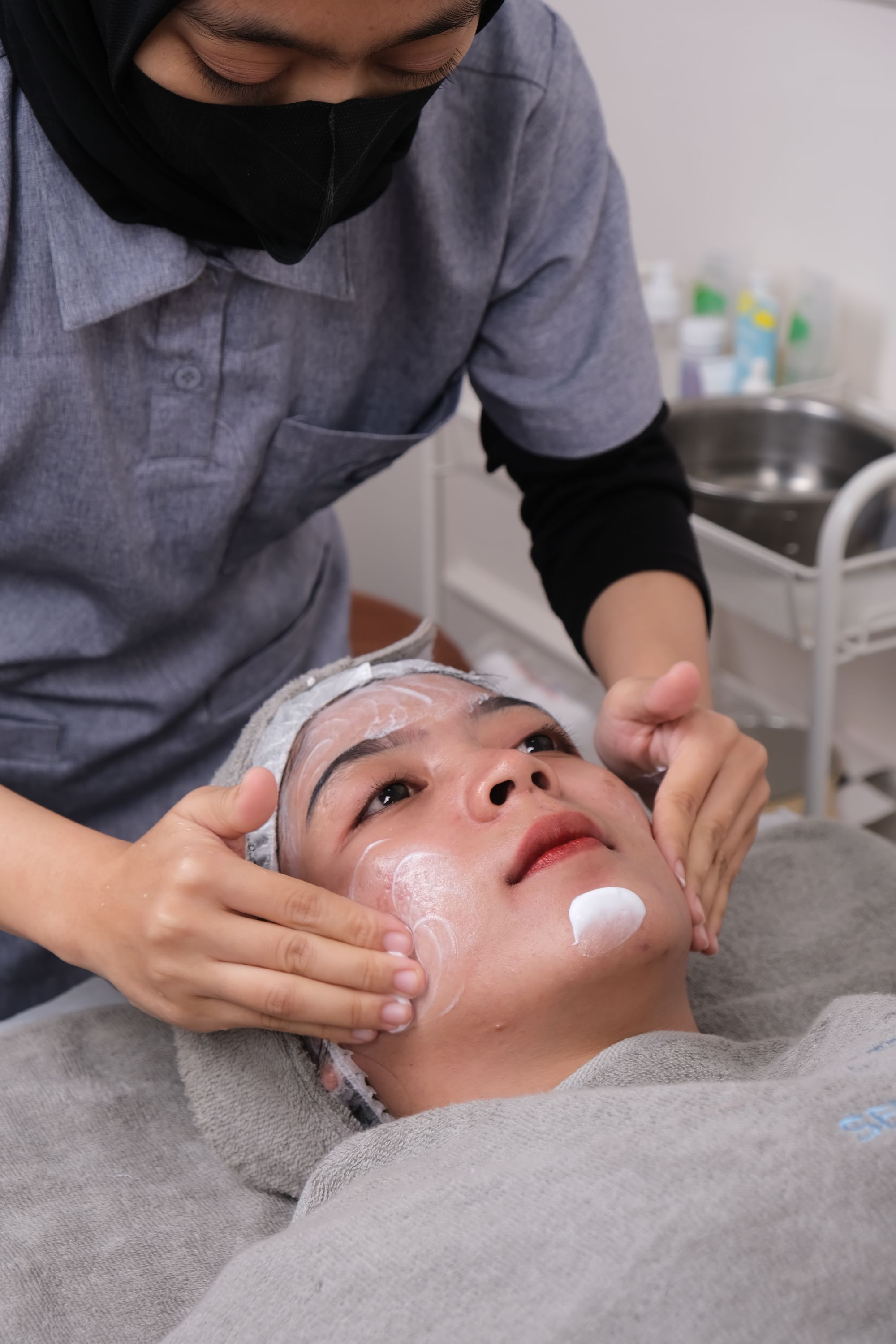Professional esthetician performing a facial treatment in a clean, calm skincare studio